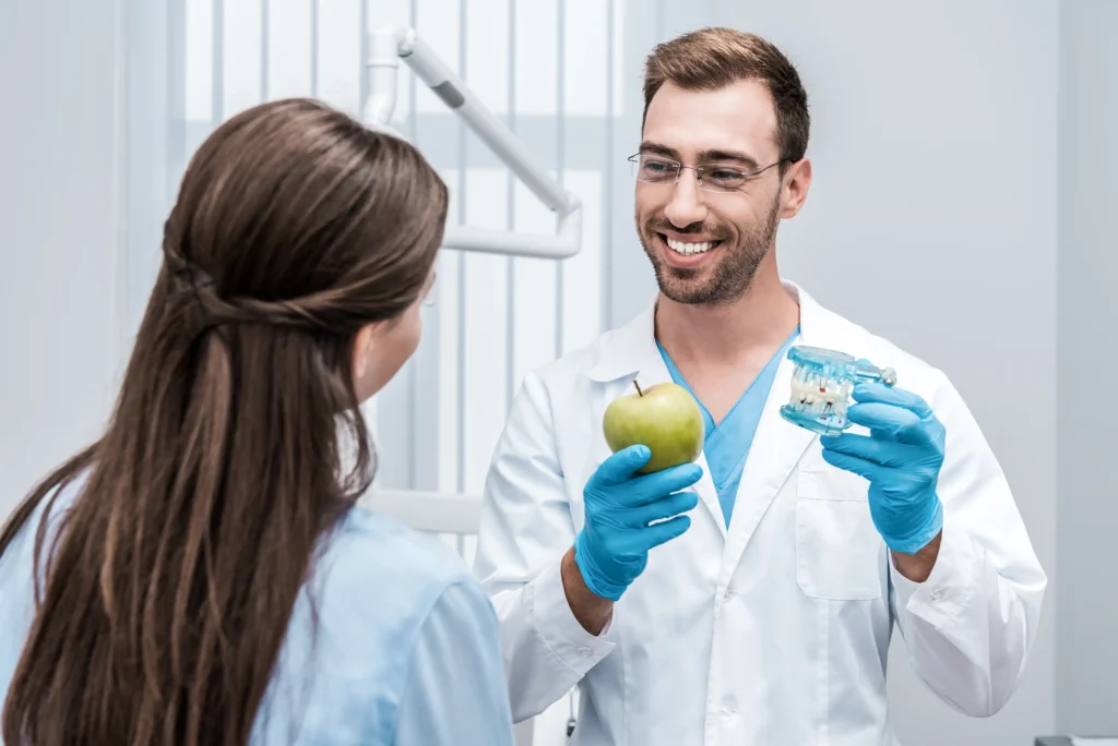 A dentist explaining oral care to a patient using a clear dental teeth model.