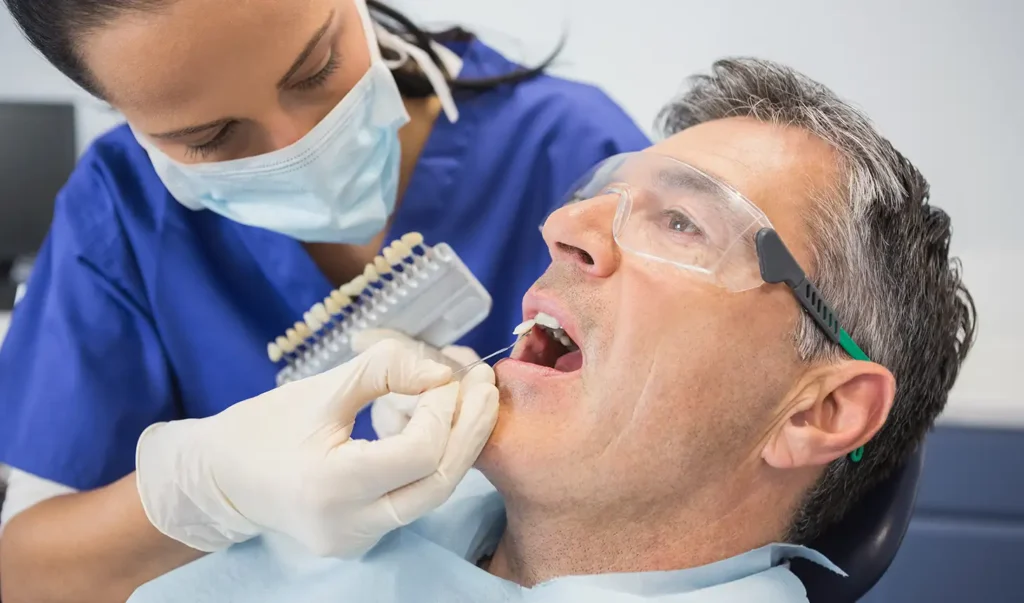 Dentist selecting a custom color shade for a dental implant crown.