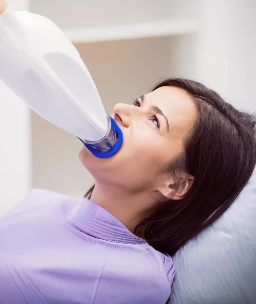 Patient lying in dental chair with an intraoral X-ray sensor placed in her mouth during imaging