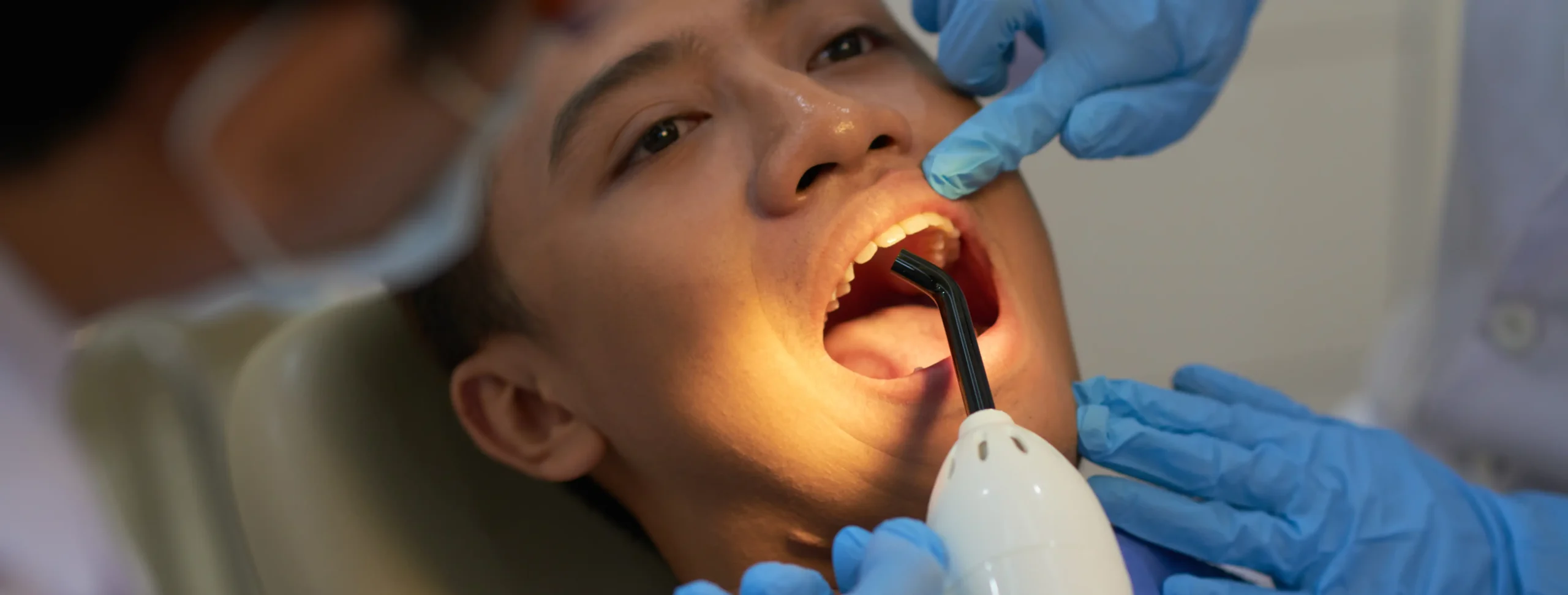 Dentist using an intraoral light to examine a young patient's teeth for early signs of decay