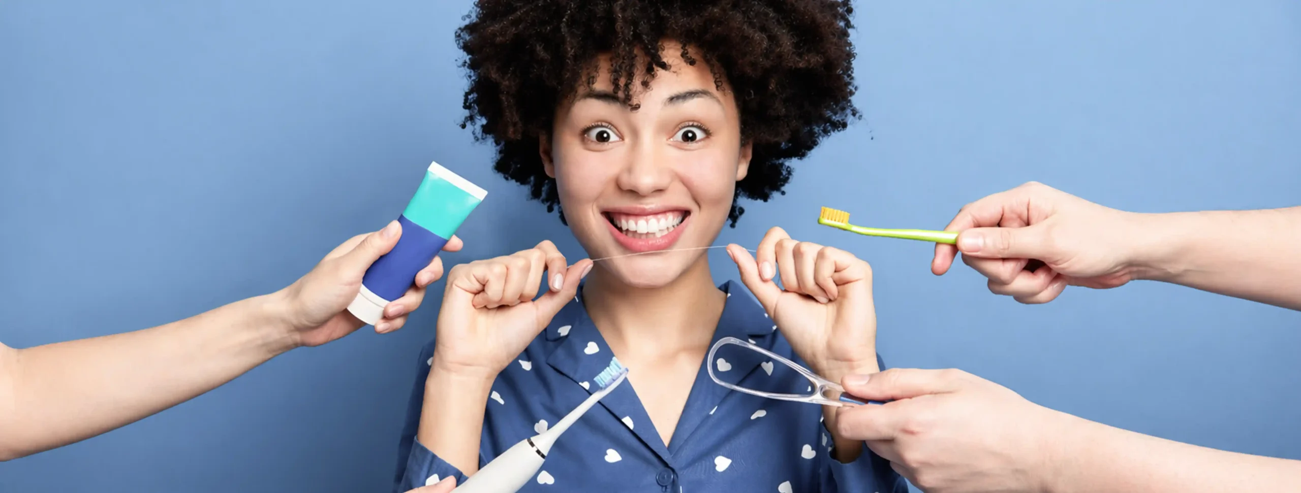Smiling woman surrounded by hands offering oral hygiene products including toothpaste, toothbrushes, floss, and a mouthguard