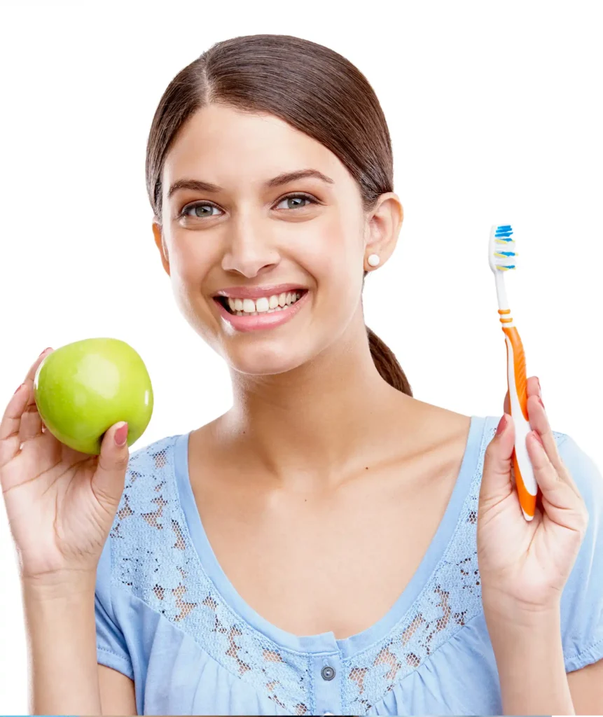 Smiling young woman holding a green apple in one hand and a toothbrush in the other