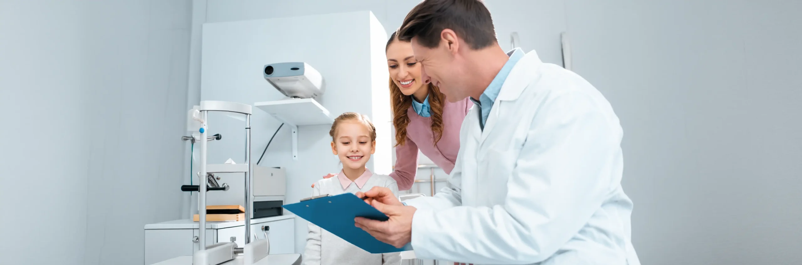 Dentist showing a clipboard to a smiling child and her parent