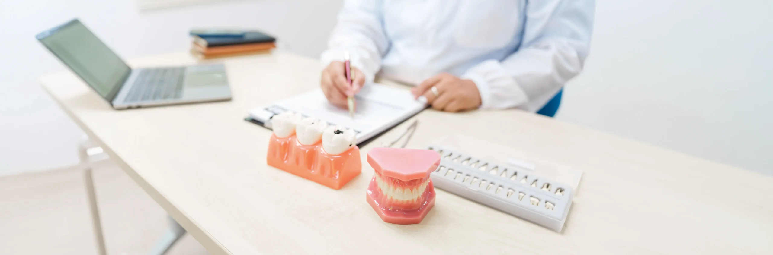 Dentist consulting on implant supported dentures with dental models on desk.