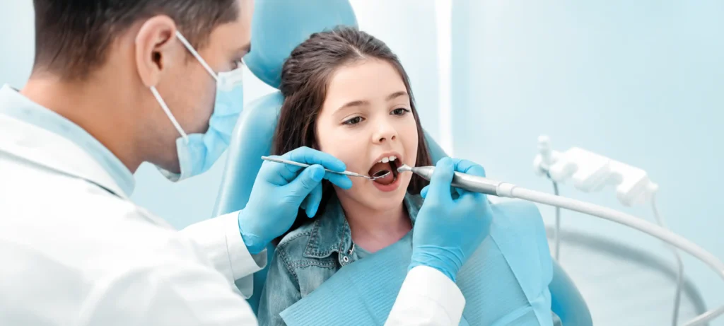 Dentist examining a young girl's teeth in a dental chair