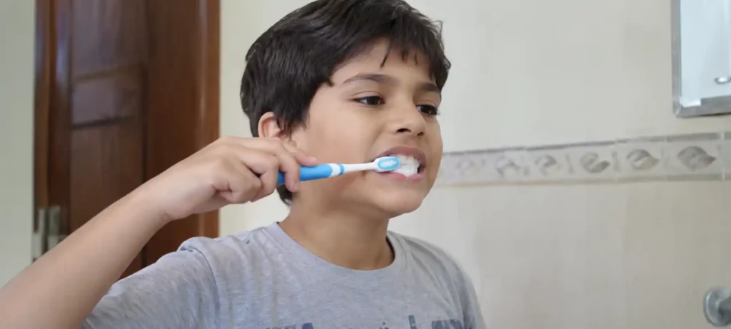 Boy brushing his teeth with a blue toothbrush at home