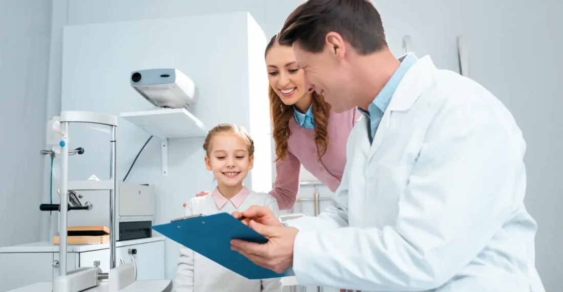 Dentist showing a clipboard to a smiling child and her parent