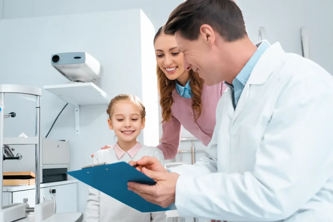 Dentist showing a clipboard to a smiling child and her parent