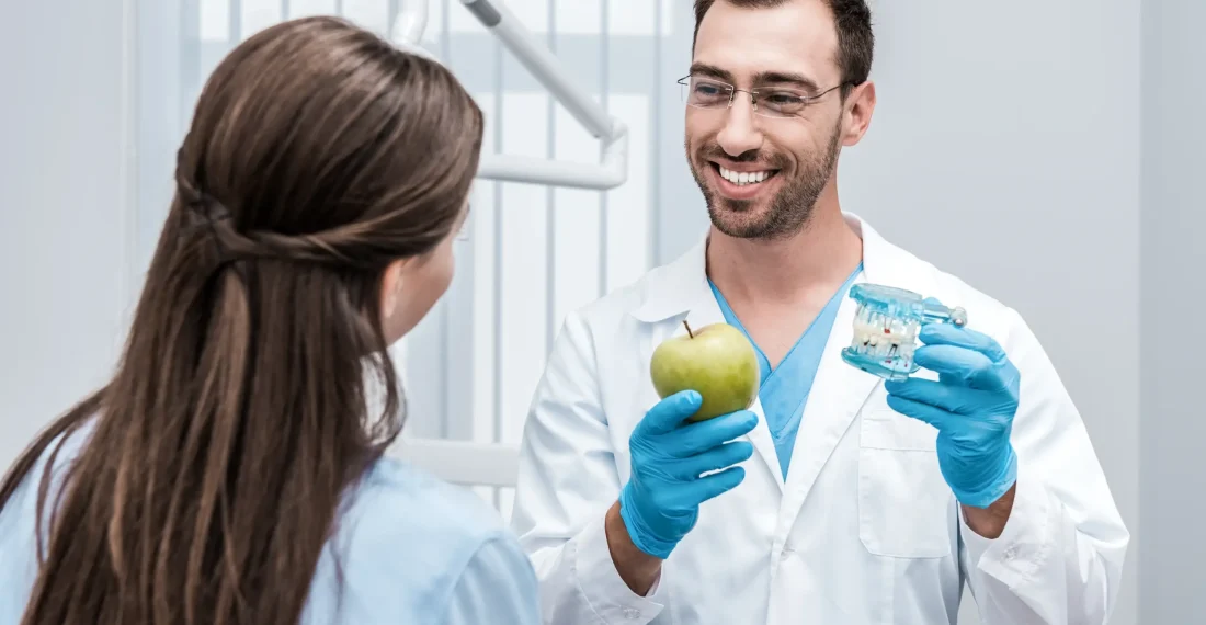A dentist explaining oral care to a patient using a clear dental teeth model.