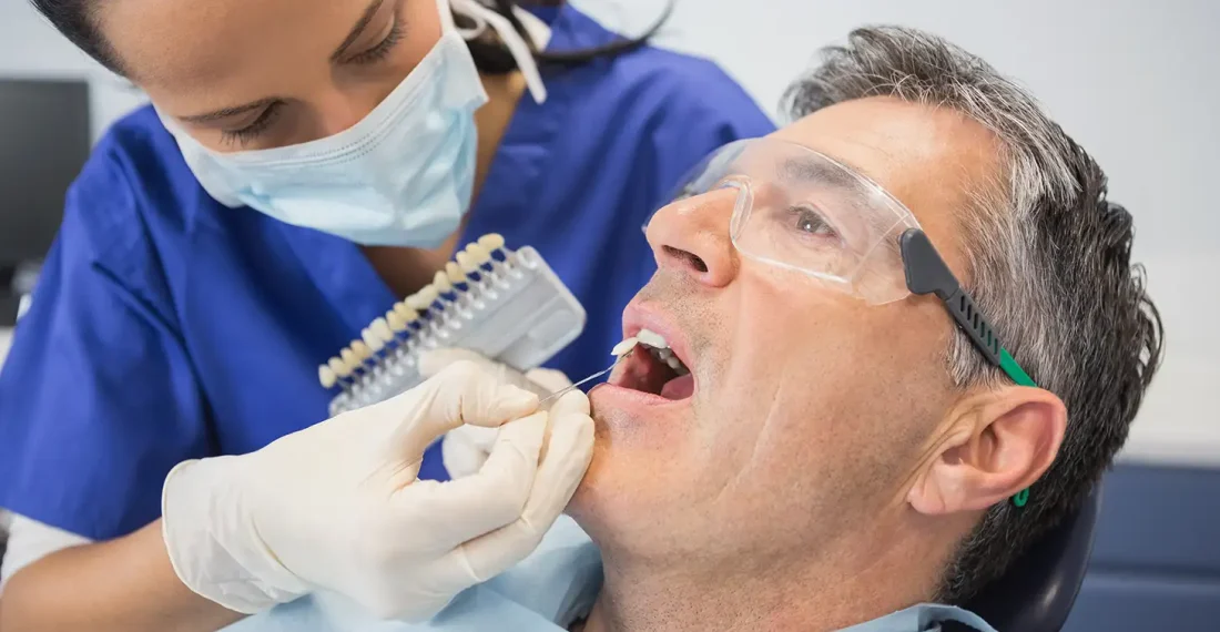 Dentist selecting a custom color shade for a dental implant crown.