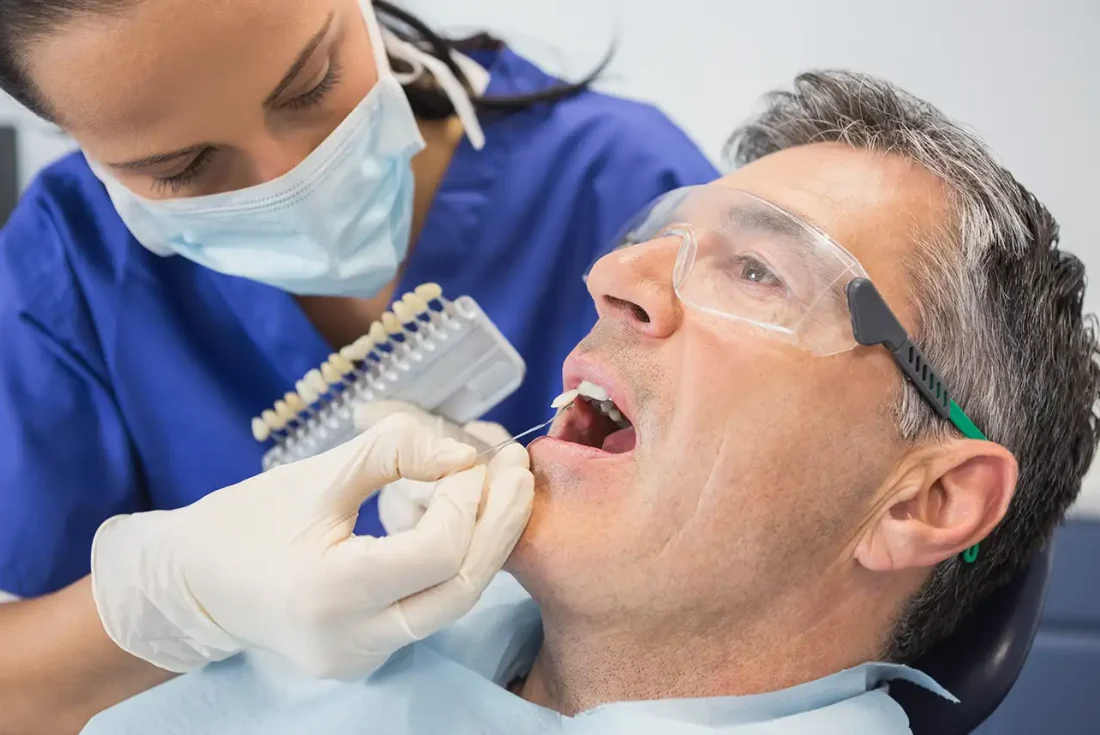 Dentist selecting a custom color shade for a dental implant crown.